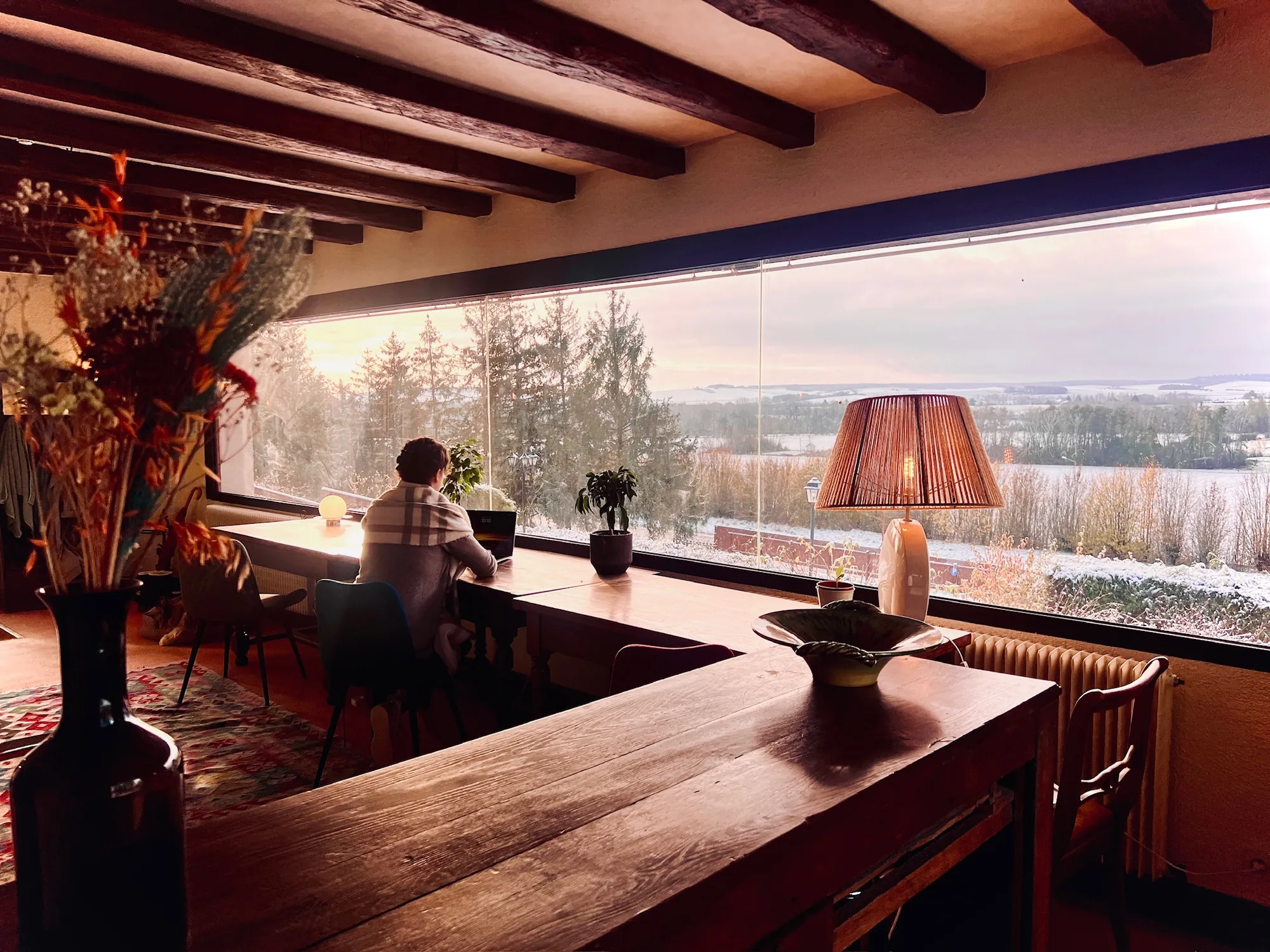 Working at the long table by the picture window at Foray, snow over the valley in the last of the afternoon light